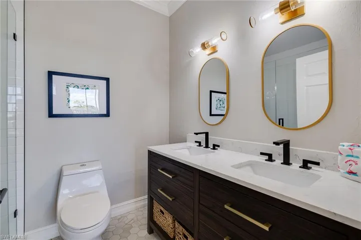 Full bathroom with double vanity, ornamental molding, and light tile patterned flooring