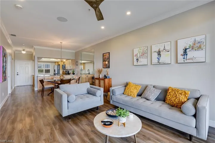 Living room with crown molding, wood finished floors, recessed lighting, and a ceiling fan