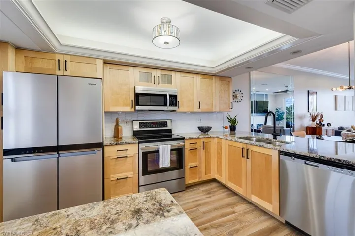 Kitchen featuring light brown cabinetry, stainless steel appliances, and crown molding