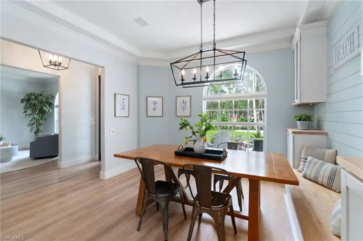 Natural light pours into the dining space adorned with custom lighting and custom wood detailing.