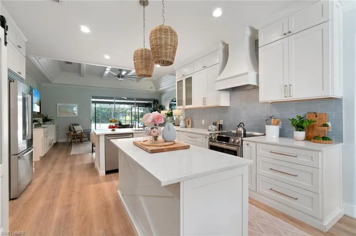 Large center island adorned with quartz countertops, Bosch appliances, and custom wood range hood