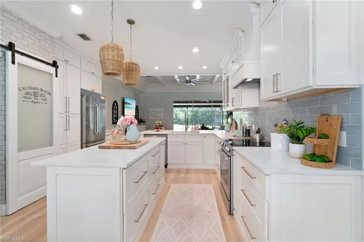 Storage! White quartz countertops, custom WOOD range hood, and barn doors shelter the laundry room