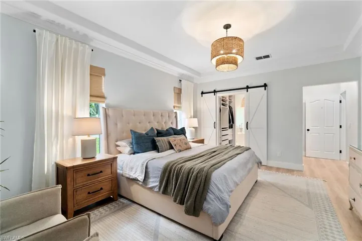 Barn doors open to the custom closet space, leading to the spa-like primary bath