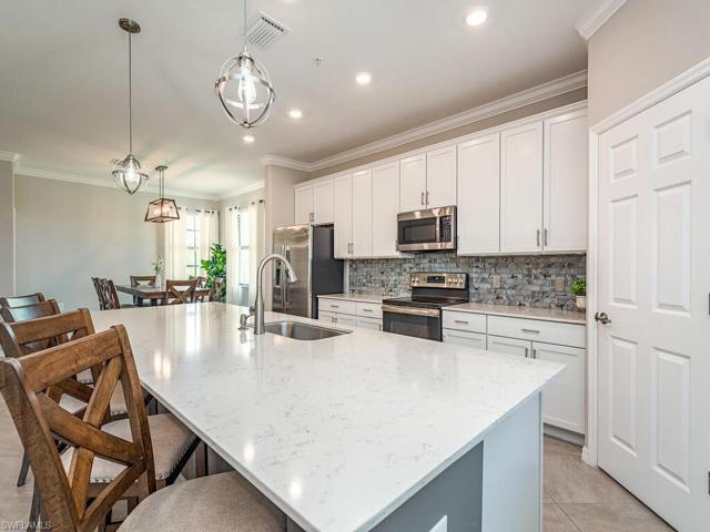 Kitchen with magnificent quartz countertops, stainless steel appliances, glass backsplash, walk-in pantry and accent lighting fixtures