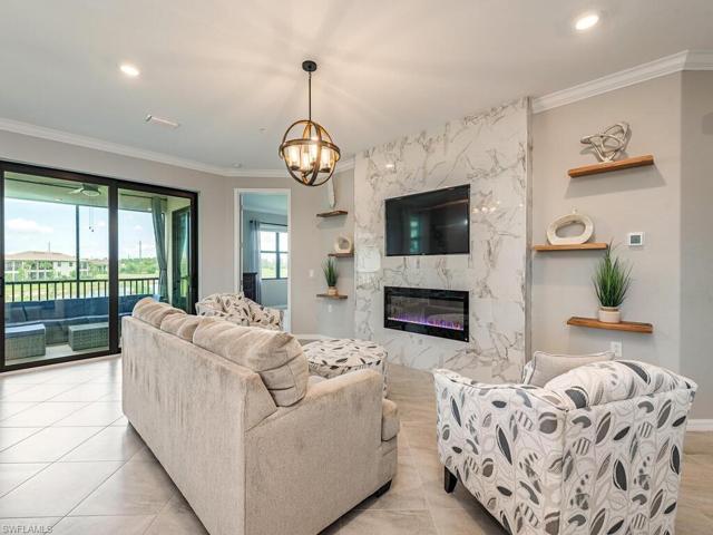 Living area featuring a built-in tv wall tiled in marble design with electric fireplace and custom shelving