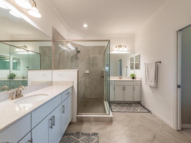 The primary bedroom features an incredible granite countertop double vanity, splendid tile floors and spacious glass encased shower