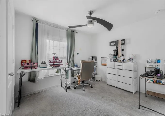 Carpeted home office featuring ceiling fan