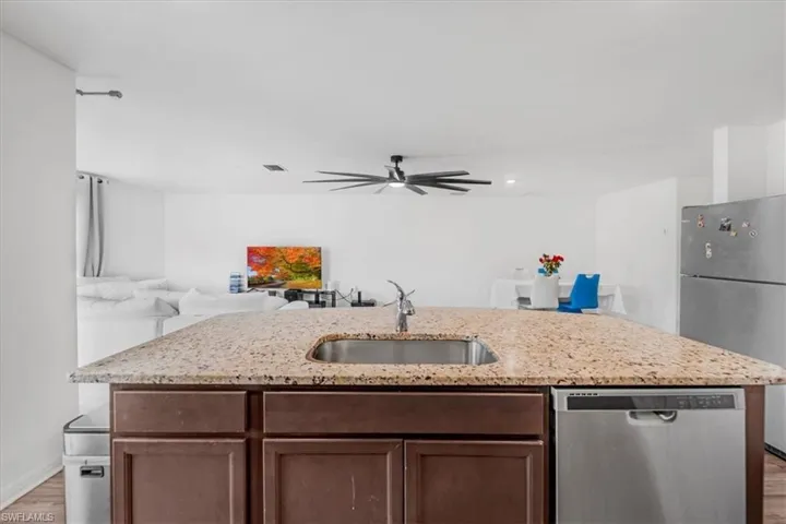 Kitchen featuring stainless steel appliances, an island with sink, light wood-style flooring, and open floor plan