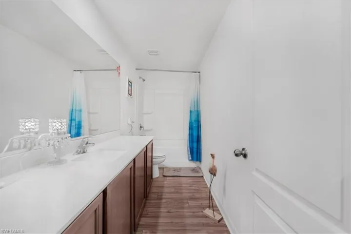 Full bath with vanity, light wood-style floors, and shower / tub combo with curtain