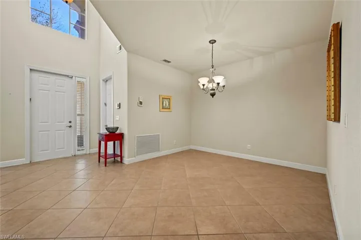 Entryway with a high ceiling, light tile patterned flooring, and a chandelier in the formal dining area