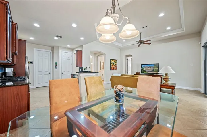 Dining area featuring recessed lighting, arched walkways, light tile patterned flooring, ceiling fan, and a chandelier