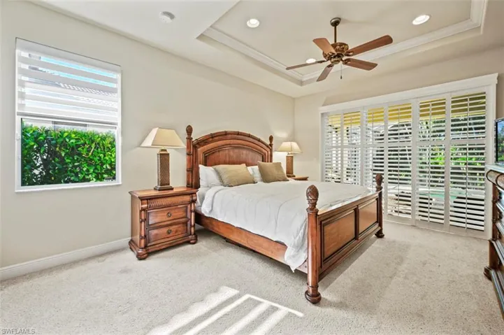 Carpeted bedroom featuring access to exterior, a raised ceiling, a ceiling fan, recessed lighting, and ornamental molding