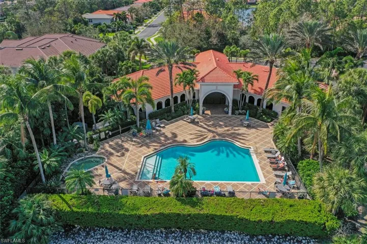 Community pool featuring a patio, a hot tub, and view of wooded area