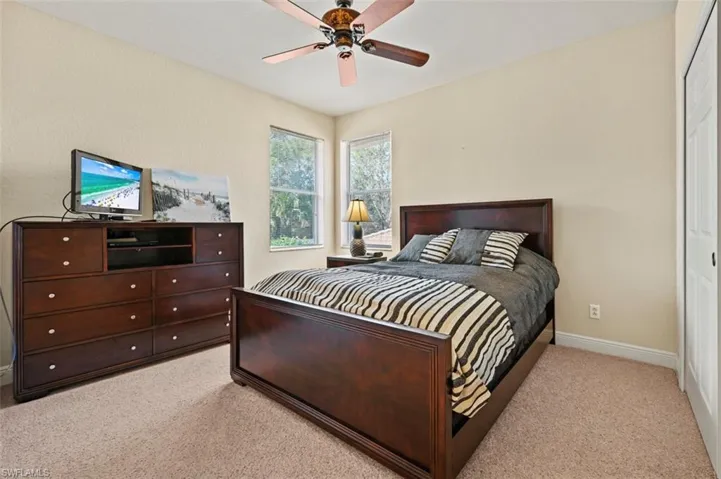 Bedroom with light carpet, ceiling fan, and a closet
