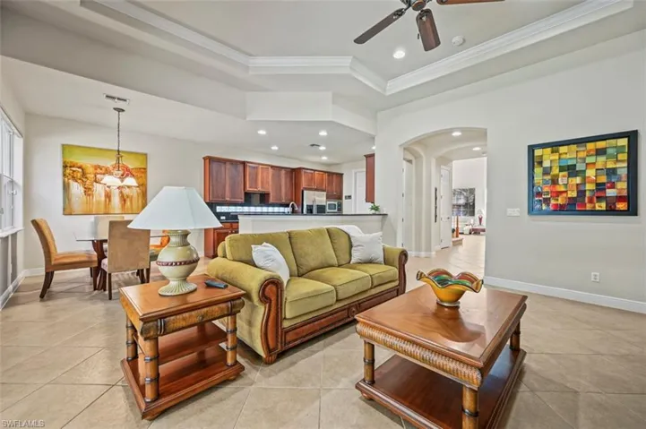 Living area with arched walkways, recessed lighting, a tray ceiling, a chandelier, and crown molding