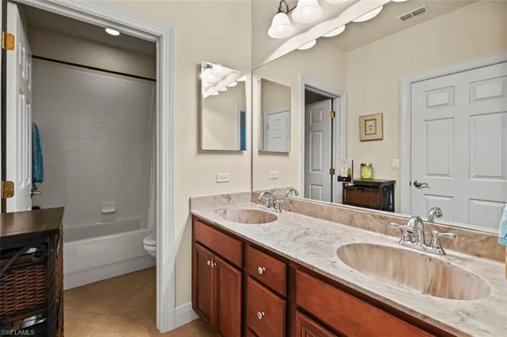 Bathroom featuring double vanity, light tile patterned flooring, and shower / bath combo with shower curtain