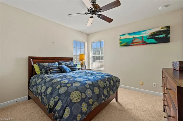 Bedroom with light colored carpet, a textured wall, and ceiling fan