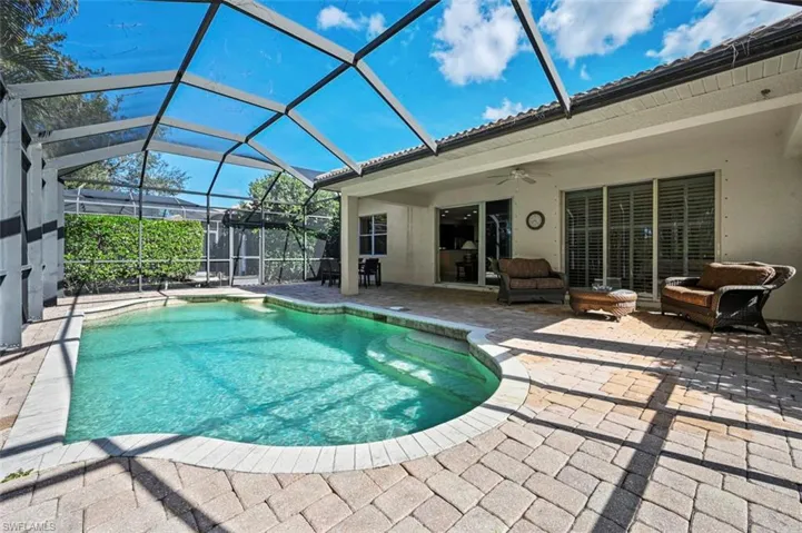 Swimming pool with screen enclosure, a sunroom, a patio area, and an outdoor living space