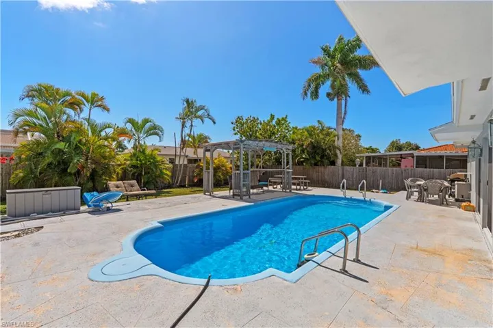 View of pool with patio surround, a fenced backyard, and a pergola
