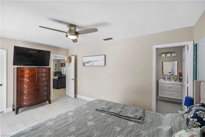 Bedroom featuring connected bathroom, a ceiling fan, and wood tiled floors