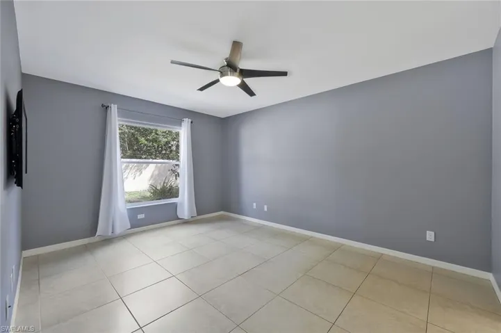 Unfurnished room with light tile patterned flooring, ceiling fan, and baseboards