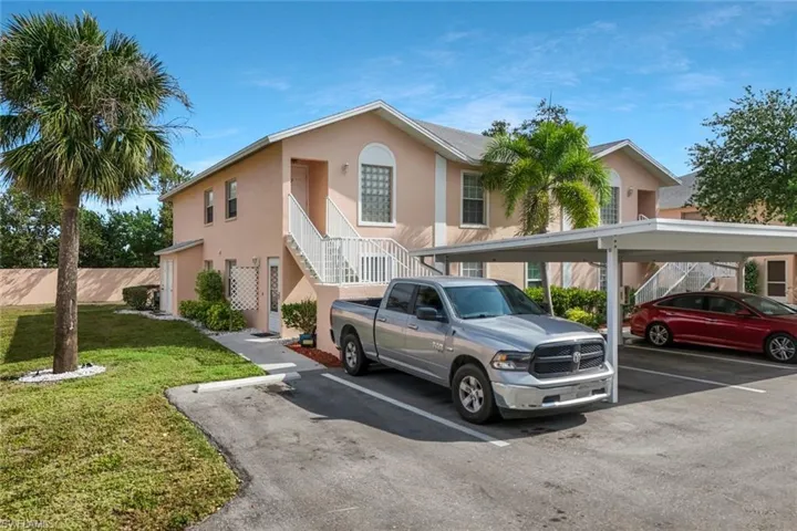 View of front of property with covered parking, a front lawn, stairway, and stucco siding