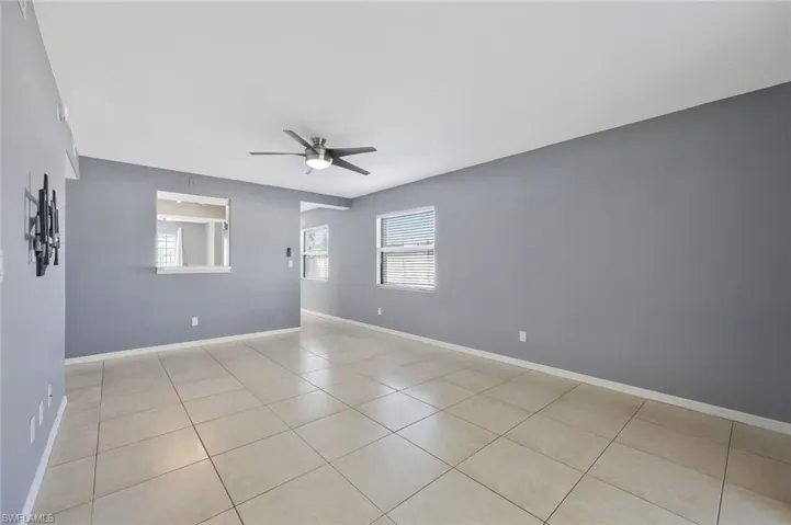Empty room with light tile patterned floors, ceiling fan, and baseboards