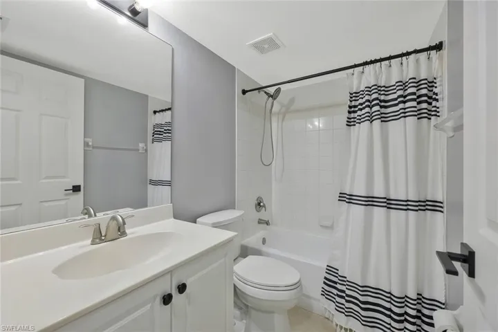 Bathroom featuring toilet, shower / bath combo, vanity, and visible vents