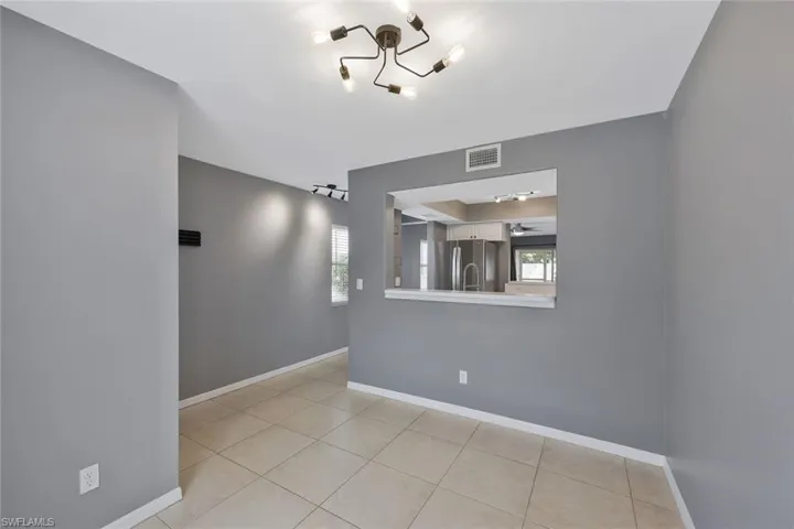 Empty room with light tile patterned floors, visible vents, and baseboards