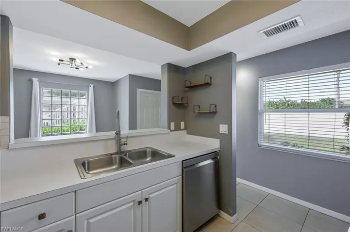 Kitchen featuring visible vents, light tile patterned flooring, light countertops, dishwasher, and a sink