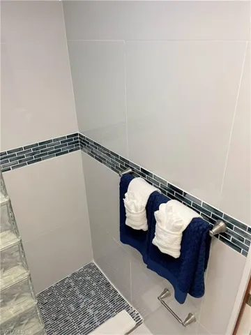 Full bath featuring tiled shower, tile walls, and tile patterned flooring