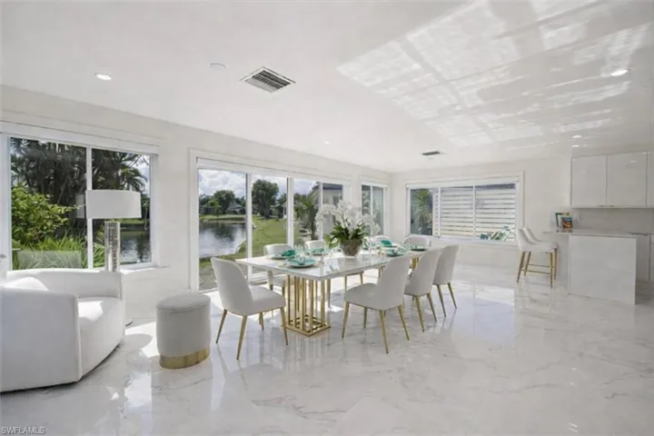 Dining space featuring light marble finish flooring, a water view, plenty of natural light, and recessed lighting