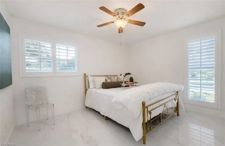 Bedroom with marble tiled flooring and a ceiling fan