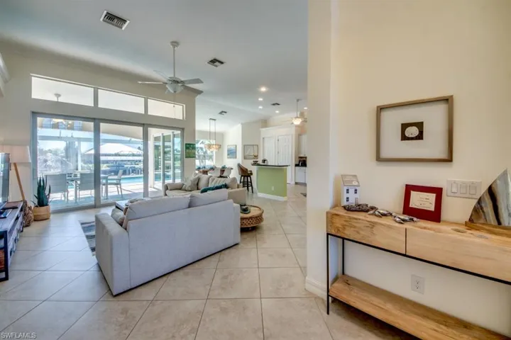 Living room with a high ceiling, ceiling fan, and tile floors