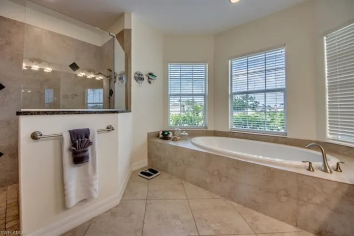 Bathroom featuring a relaxing tiled bath and tile flooring