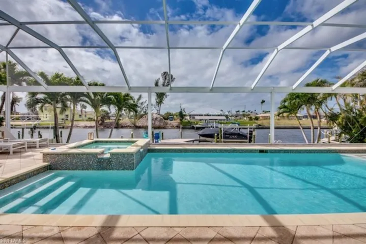 View of pool with glass enclosure and an in ground hot tub