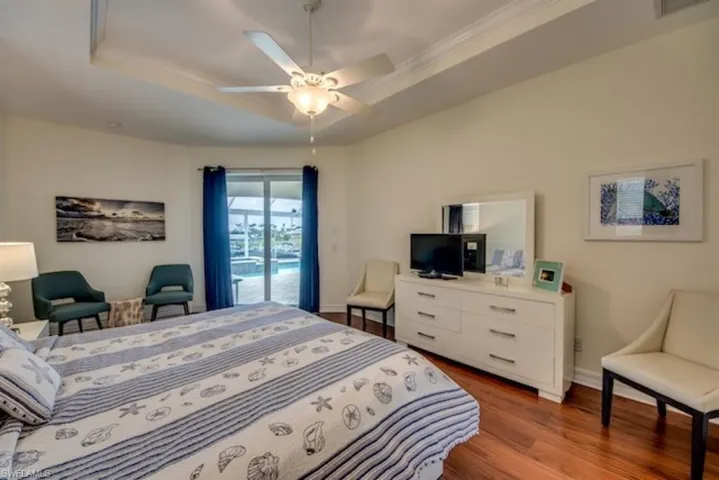 Bedroom with ceiling fan, a raised ceiling, hardwood / wood-style floors, and access to exterior
