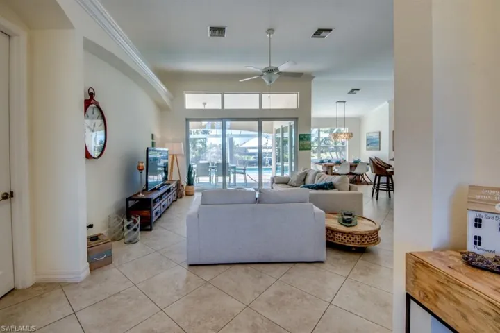 Tiled living room featuring ceiling fan with notable chandelier and ornamental molding