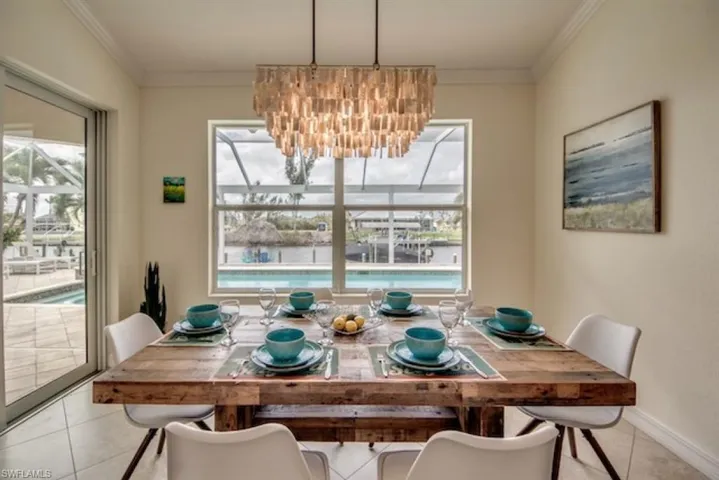 Tiled dining room featuring crown molding and a chandelier