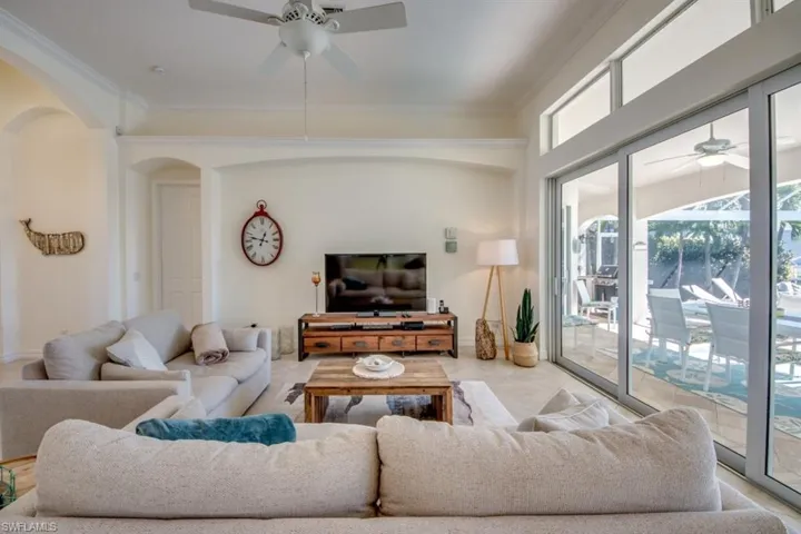 Living room with ornamental molding, ceiling fan, and light tile floors