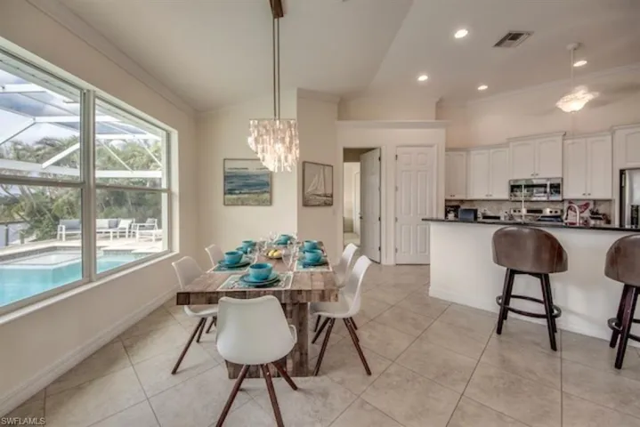 Tiled dining space featuring vaulted ceiling and an inviting chandelier