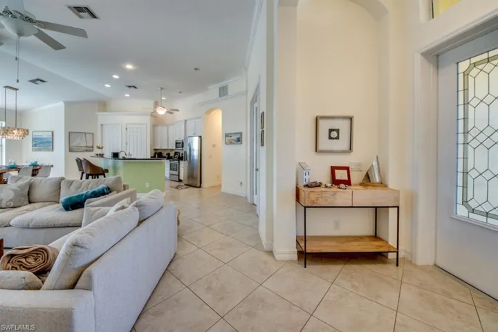 Tiled living room featuring ornamental molding and ceiling fan with notable chandelier