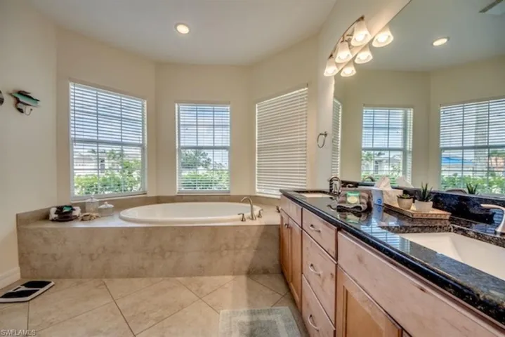 Bathroom with tile floors, double sink, oversized vanity, and tiled tub