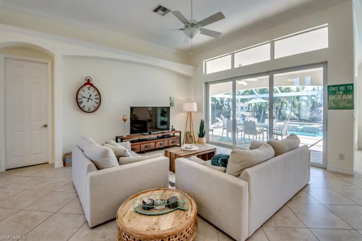 Living room featuring ornamental molding, ceiling fan, and light tile floors
