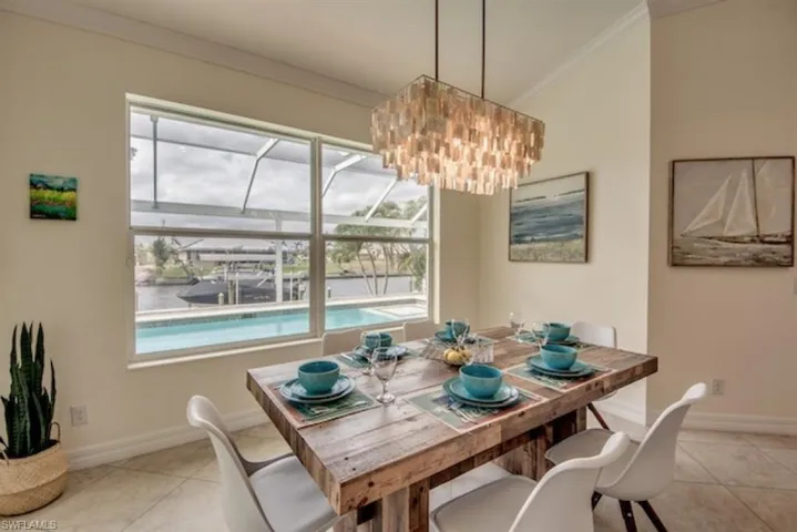 Dining space featuring ornamental molding, a chandelier, and light tile floors