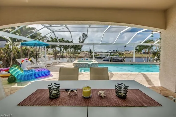View of swimming pool with a patio area, glass enclosure, and an in ground hot tub