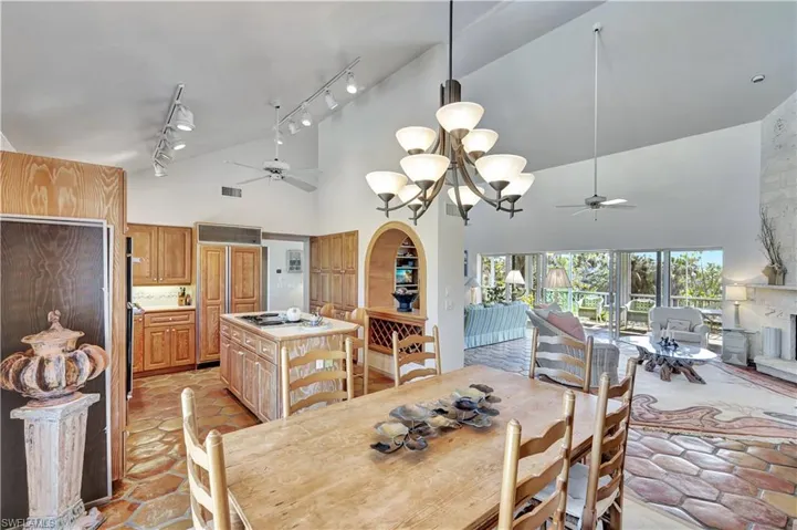 Dining room with rail lighting, ceiling fan with notable chandelier, and high vaulted ceiling