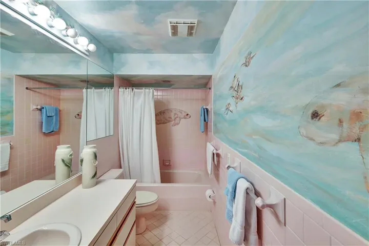 Full bathroom with tile walls, vanity, toilet, tile patterned floors, and shower / bath combo with shower curtain