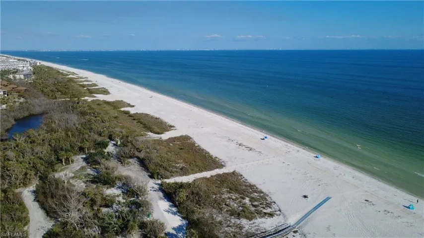 Birds eye view of property featuring a water view and a view of the beach