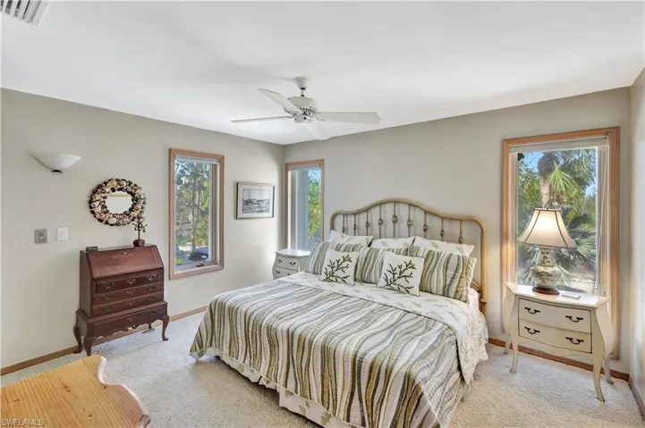 Bedroom featuring multiple windows, light colored carpet, and ceiling fan